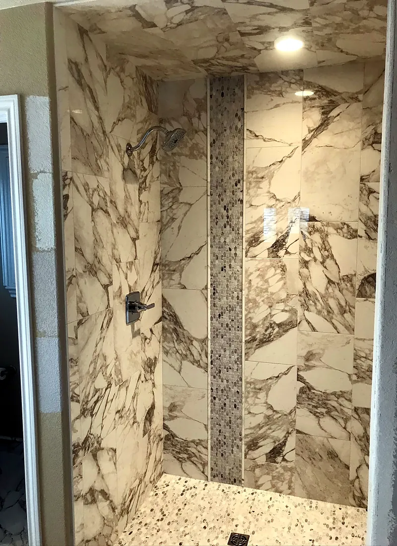 Calacatta-look shower: book-matched slabs with a mosaic inlay
